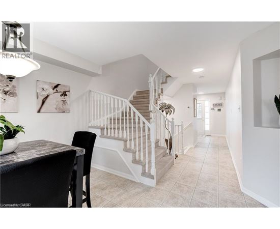 A spacious hallway with a staircase and a dining table.