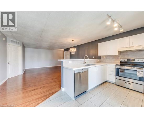 A kitchen with white cabinets and a wooden floor.