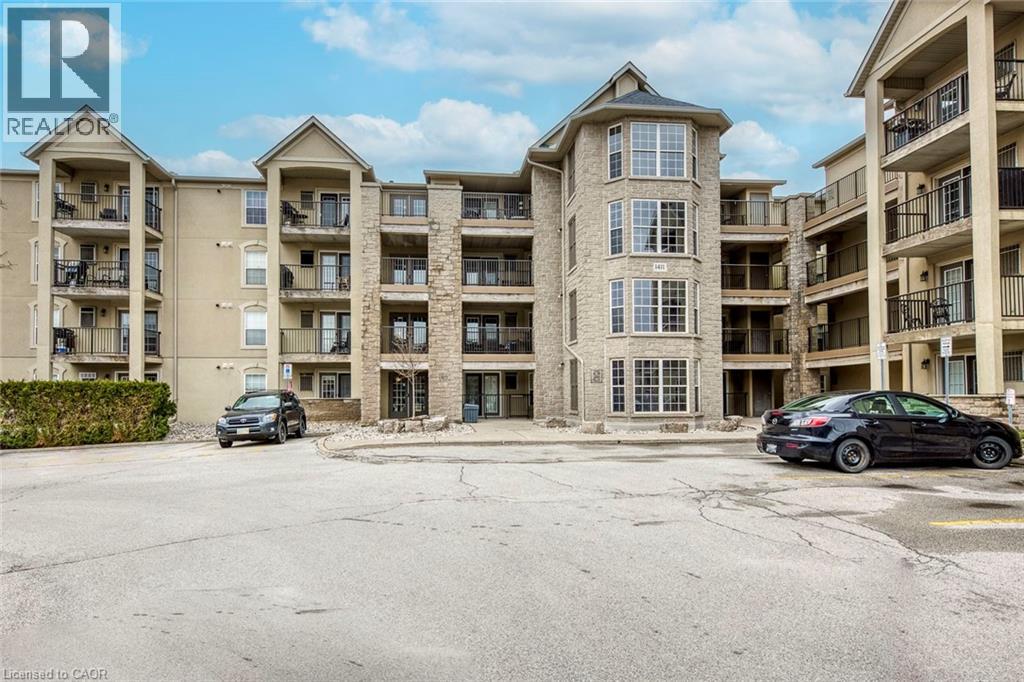 A black car is parked in the lot of a large apartment complex.