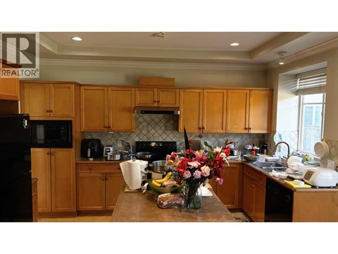 A kitchen with wooden cabinets and a black fridge.