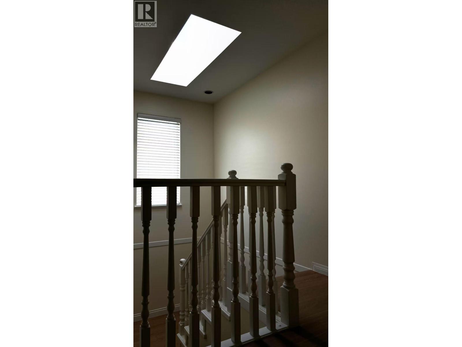 A staircase with a wooden banister and a skylight above.