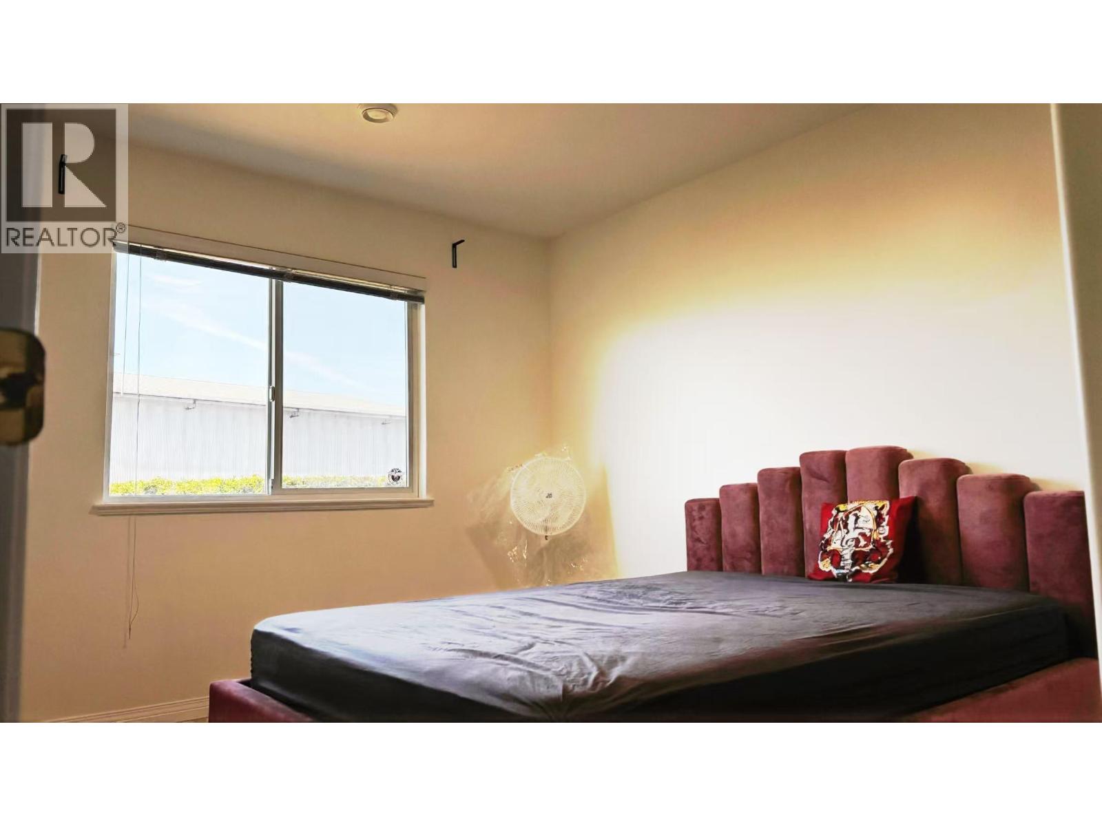 A bedroom with a red bed and a window.