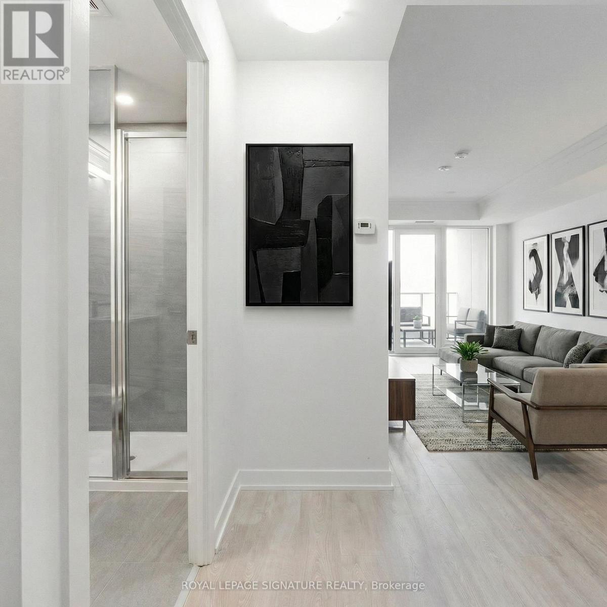 A modern living room with a glass door and a large abstract painting on the wall.