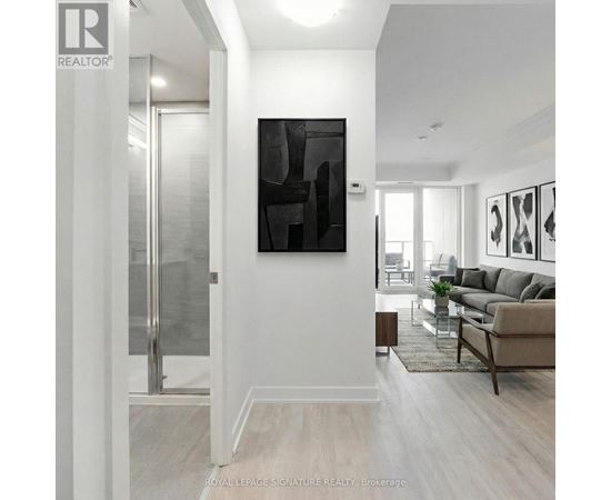 A modern living room with a glass door and a large abstract painting on the wall.