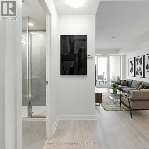 A modern living room with a glass door and a large abstract painting on the wall.