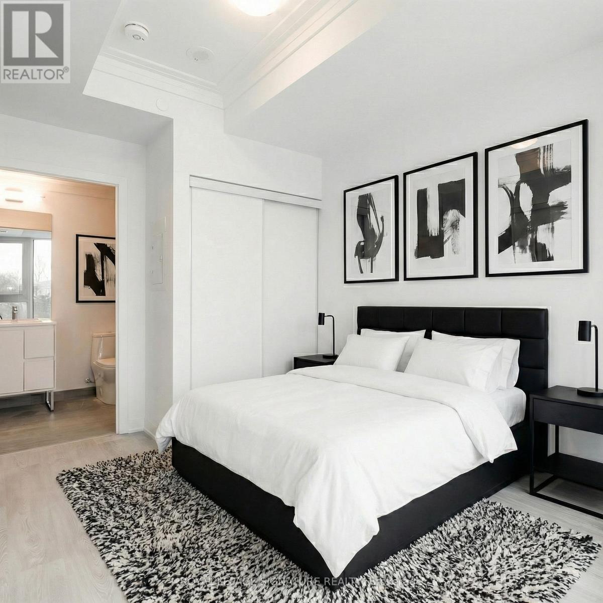 A bedroom with a large bed and three abstract paintings on the wall.