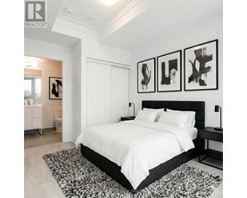 A bedroom with a large bed and three abstract paintings on the wall.