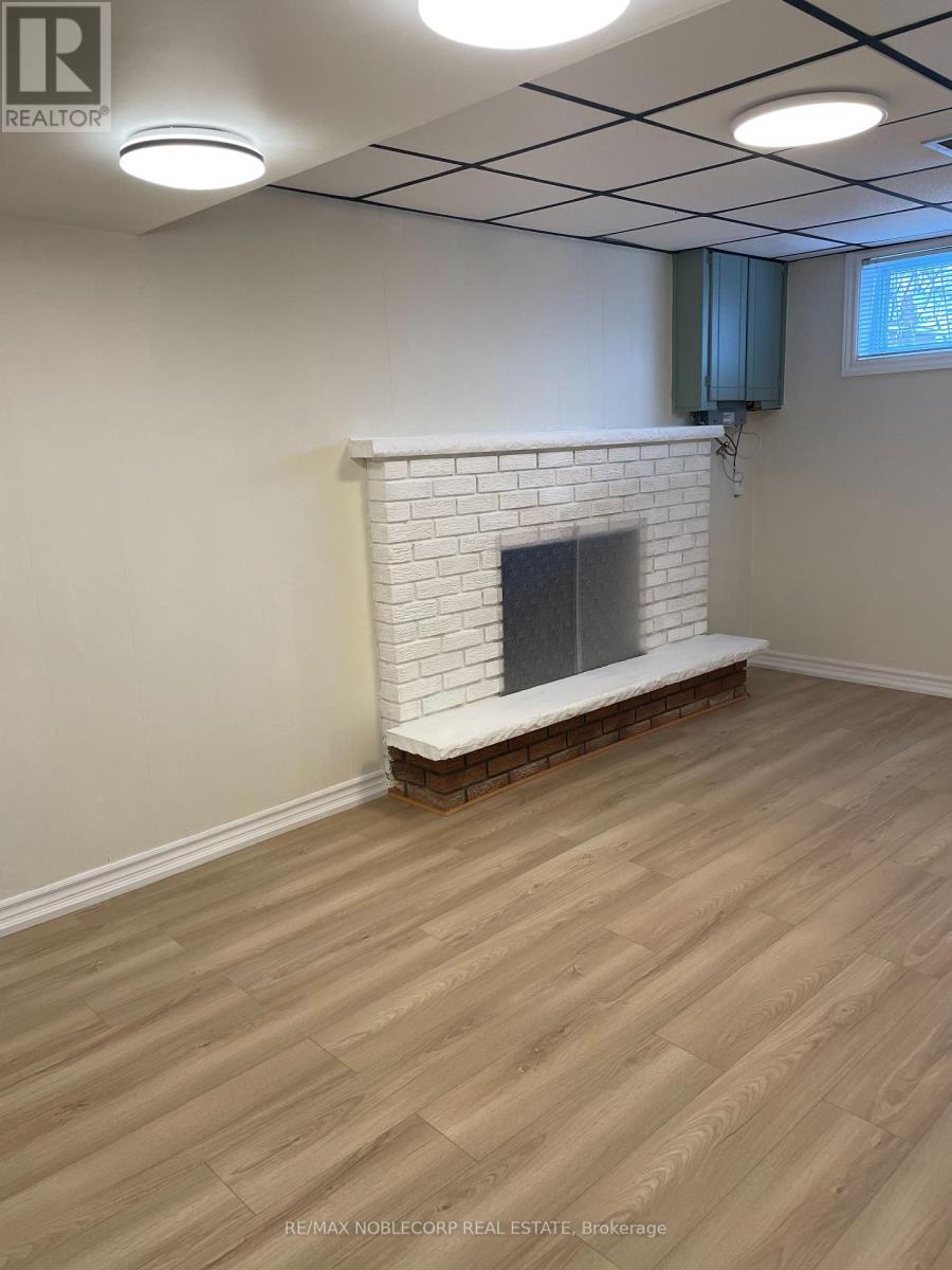 A room with a white brick fireplace and wooden flooring.