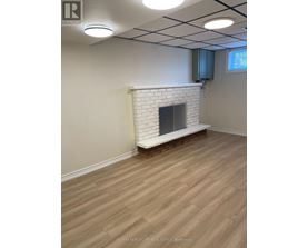 A room with a white brick fireplace and wooden flooring.