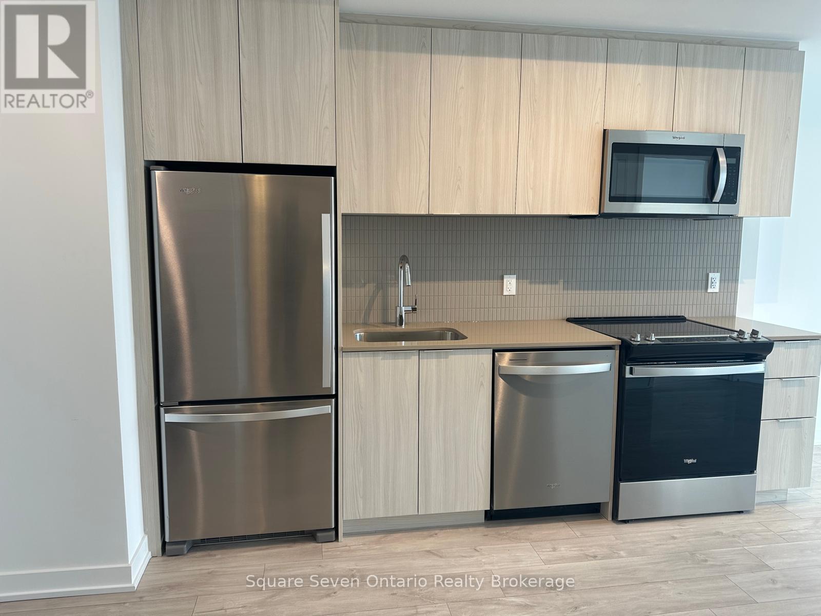 A kitchen with a stainless steel refrigerator, a sink, and a microwave.