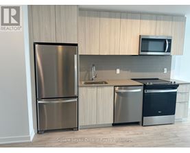 A kitchen with a stainless steel refrigerator, a sink, and a microwave.