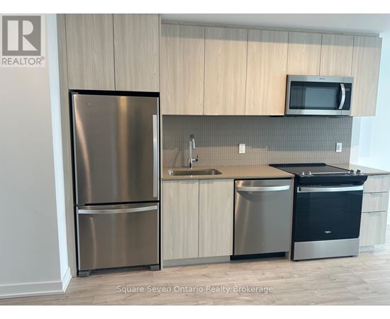 A kitchen with a stainless steel refrigerator, a sink, and a microwave.