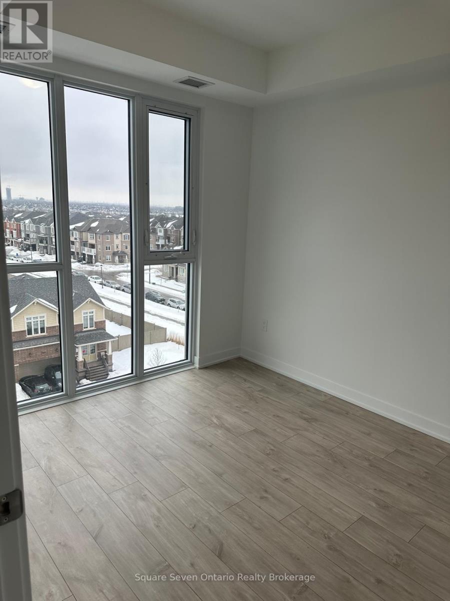 A room with a view of a residential area through large windows.