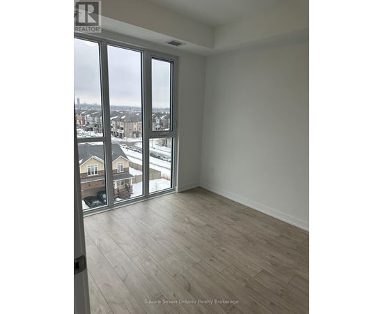 A room with a view of a residential area through large windows.