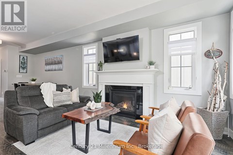 A living room with a grey couch, a coffee table, a fireplace, and a television mounted above it.