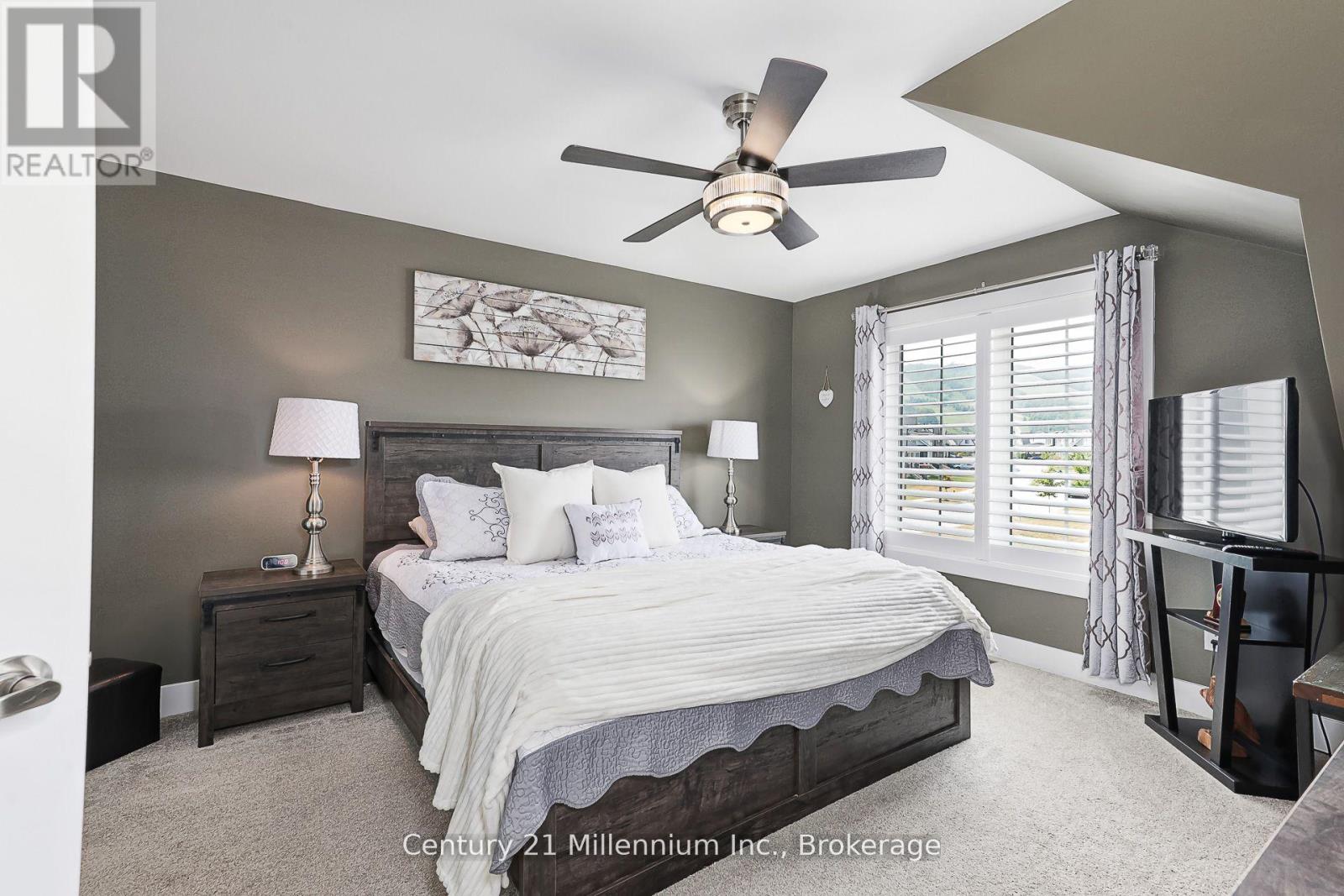A bedroom with a bed, nightstands, and a ceiling fan.