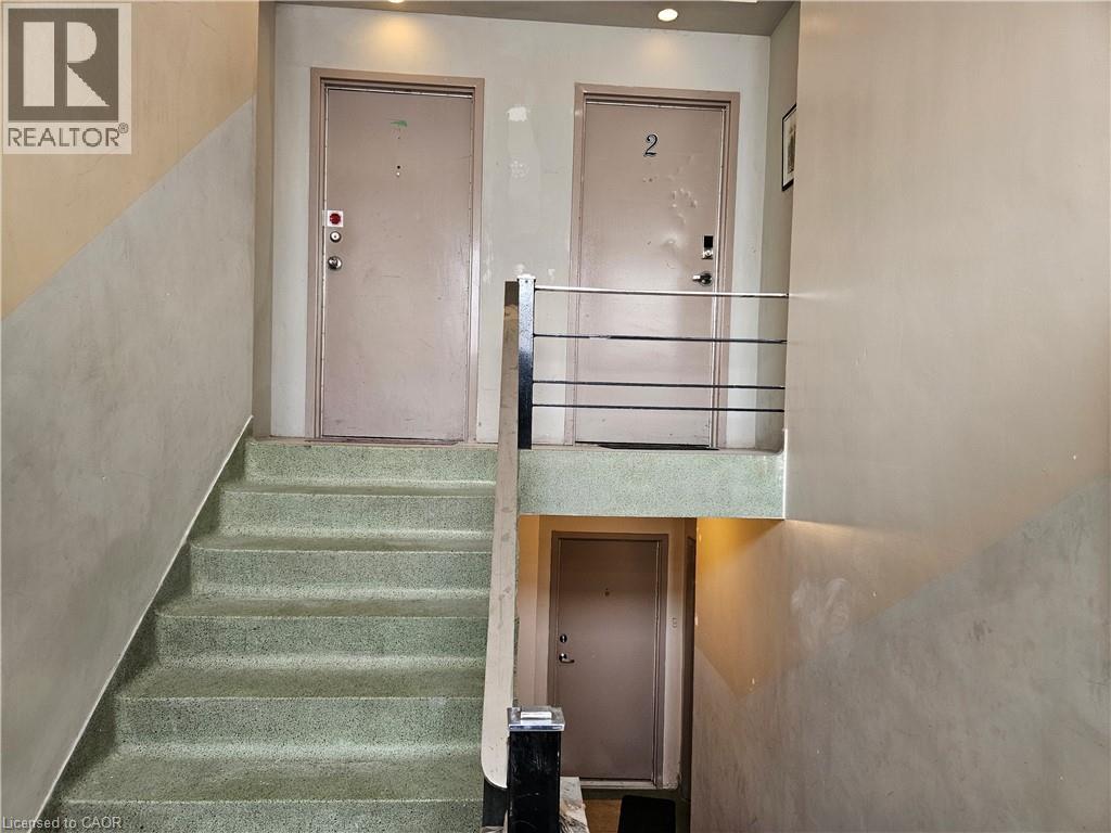 A staircase with a green carpet and a metal railing.