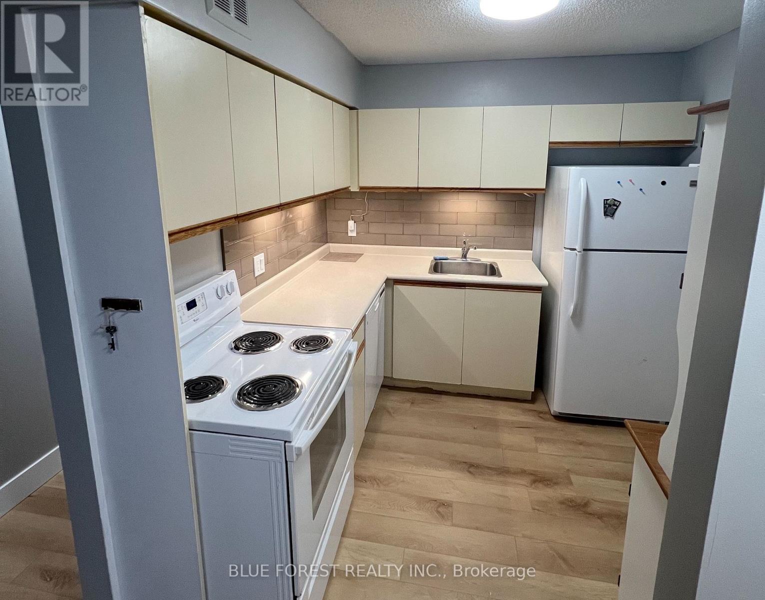 A small kitchen with a stove, sink, and refrigerator.