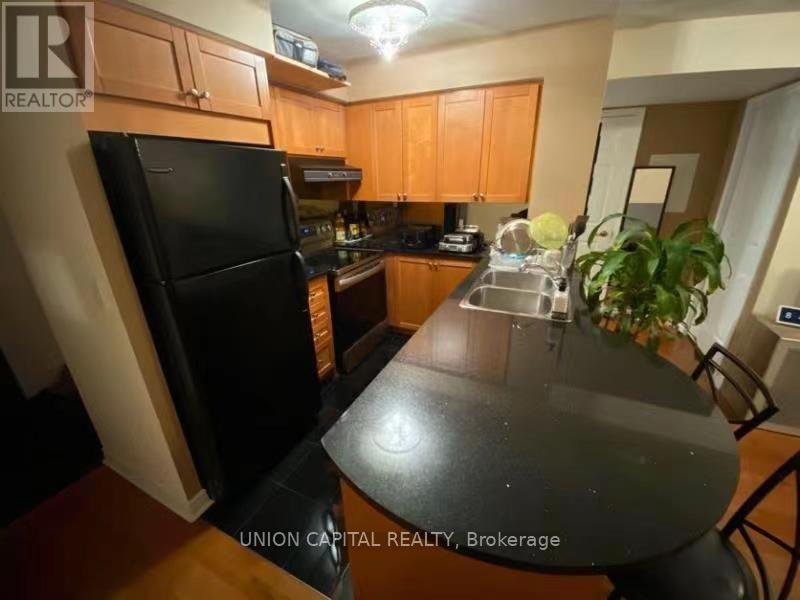 A kitchen with wooden cabinets and a black fridge.