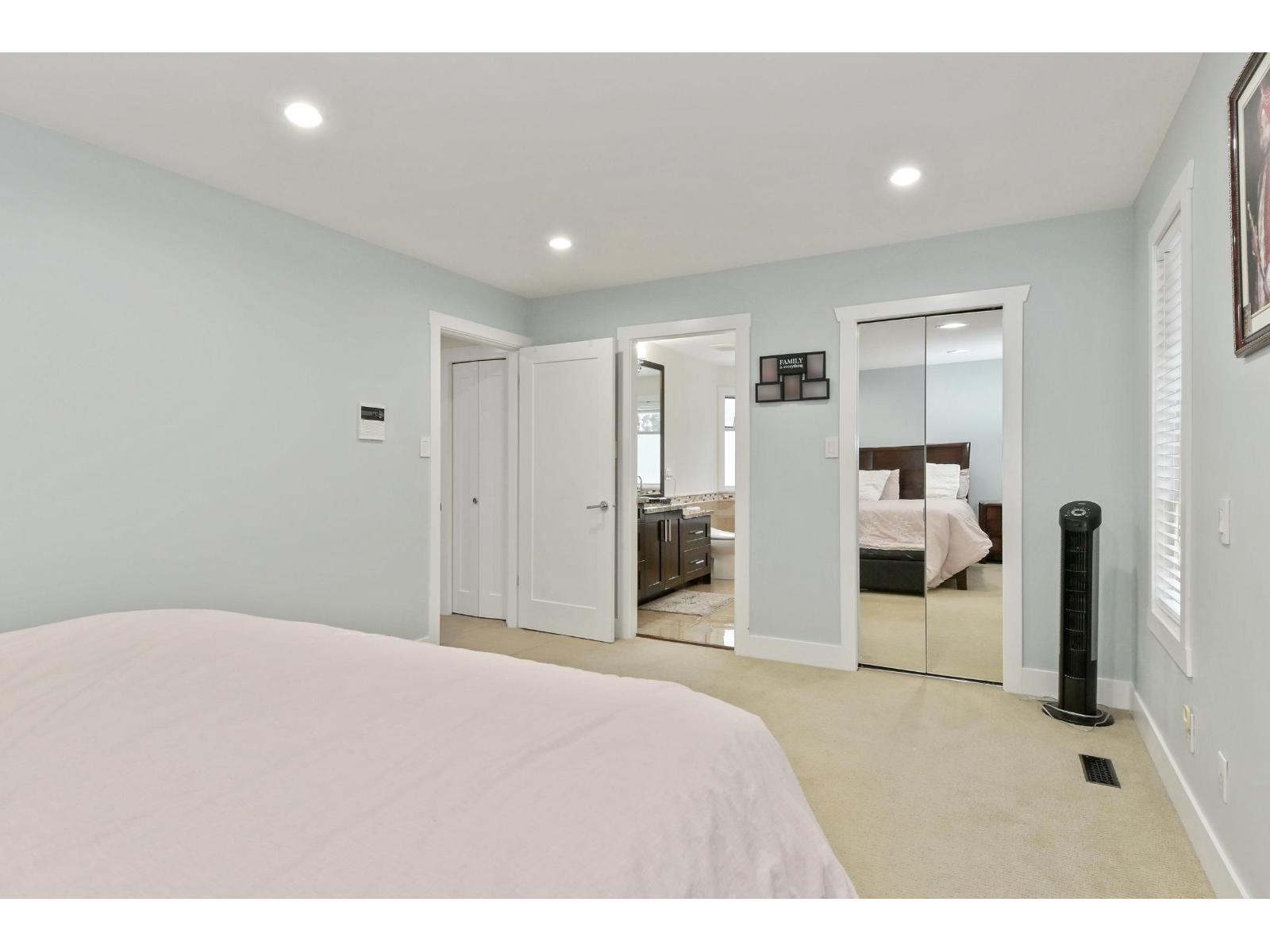 A bedroom with a large bed and a mirrored closet door.