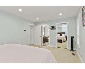 A bedroom with a large bed and a mirrored closet door.