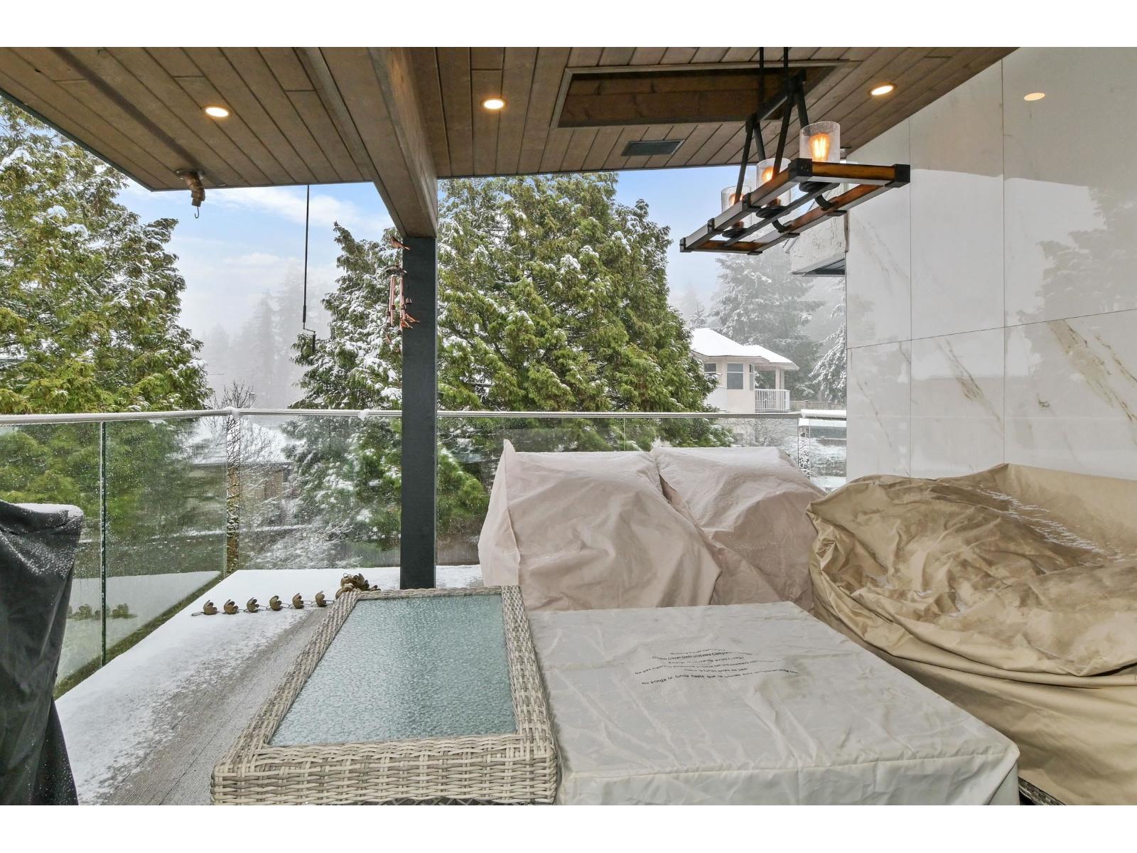 A hot tub is on a balcony with a view of a snowy landscape.