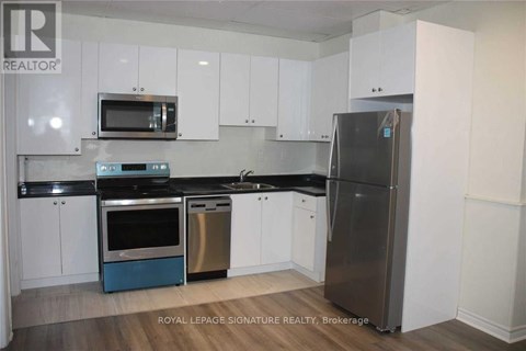 A kitchen with white cabinets and a stainless steel refrigerator.