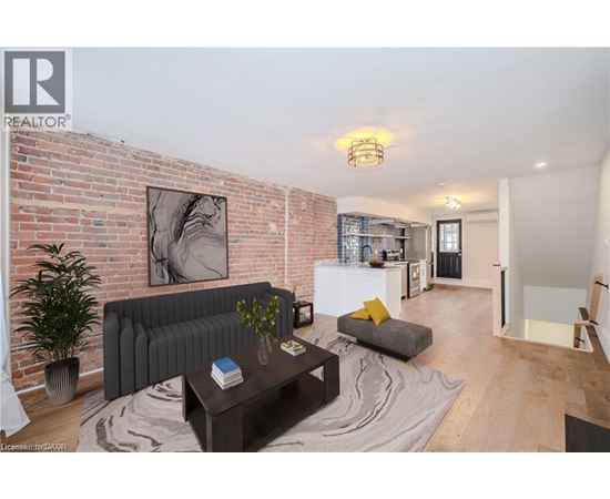 A living room with a grey couch and a coffee table in front of a brick wall.