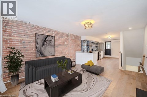A living room with a grey couch and a coffee table in front of a brick wall.
