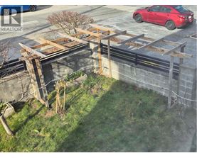 A red car is parked on the street behind a construction site.