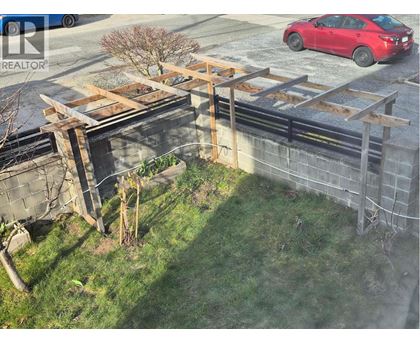 A red car is parked on the street behind a construction site.