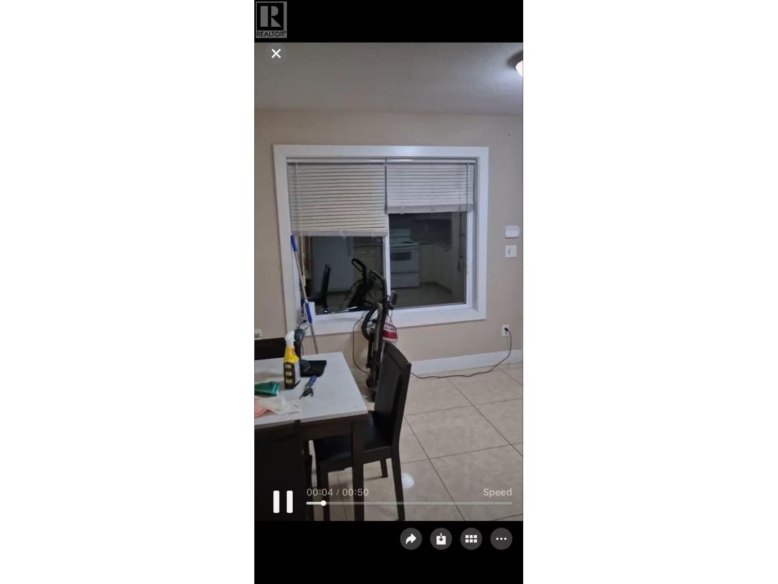 A room with a table, chairs, and a window with blinds.