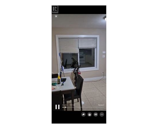 A room with a table, chairs, and a window with blinds.
