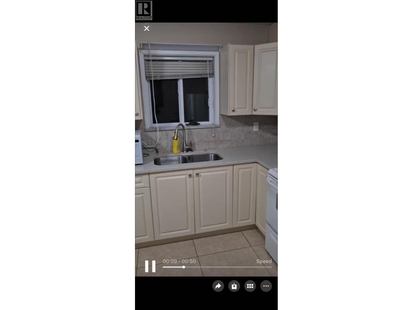 A kitchen with beige cabinets and a window above the sink.