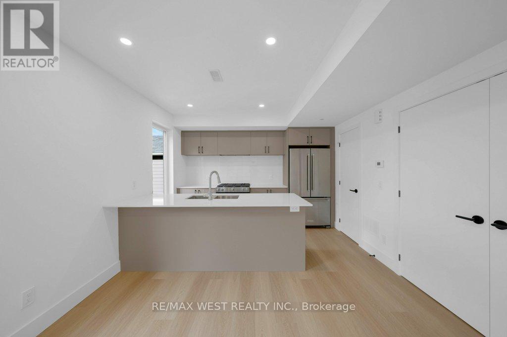A modern kitchen with white cabinets and a wooden floor.