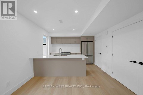 A modern kitchen with white cabinets and a wooden floor.