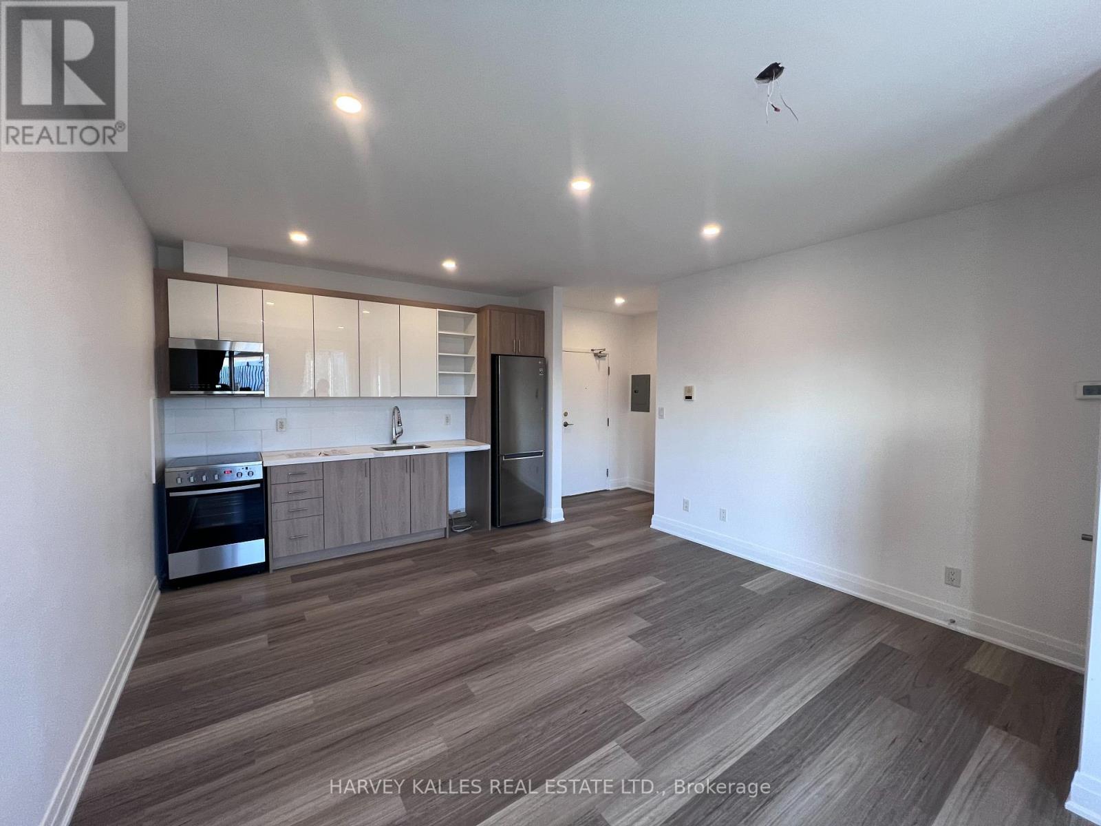 A spacious kitchen with wooden flooring and white walls.