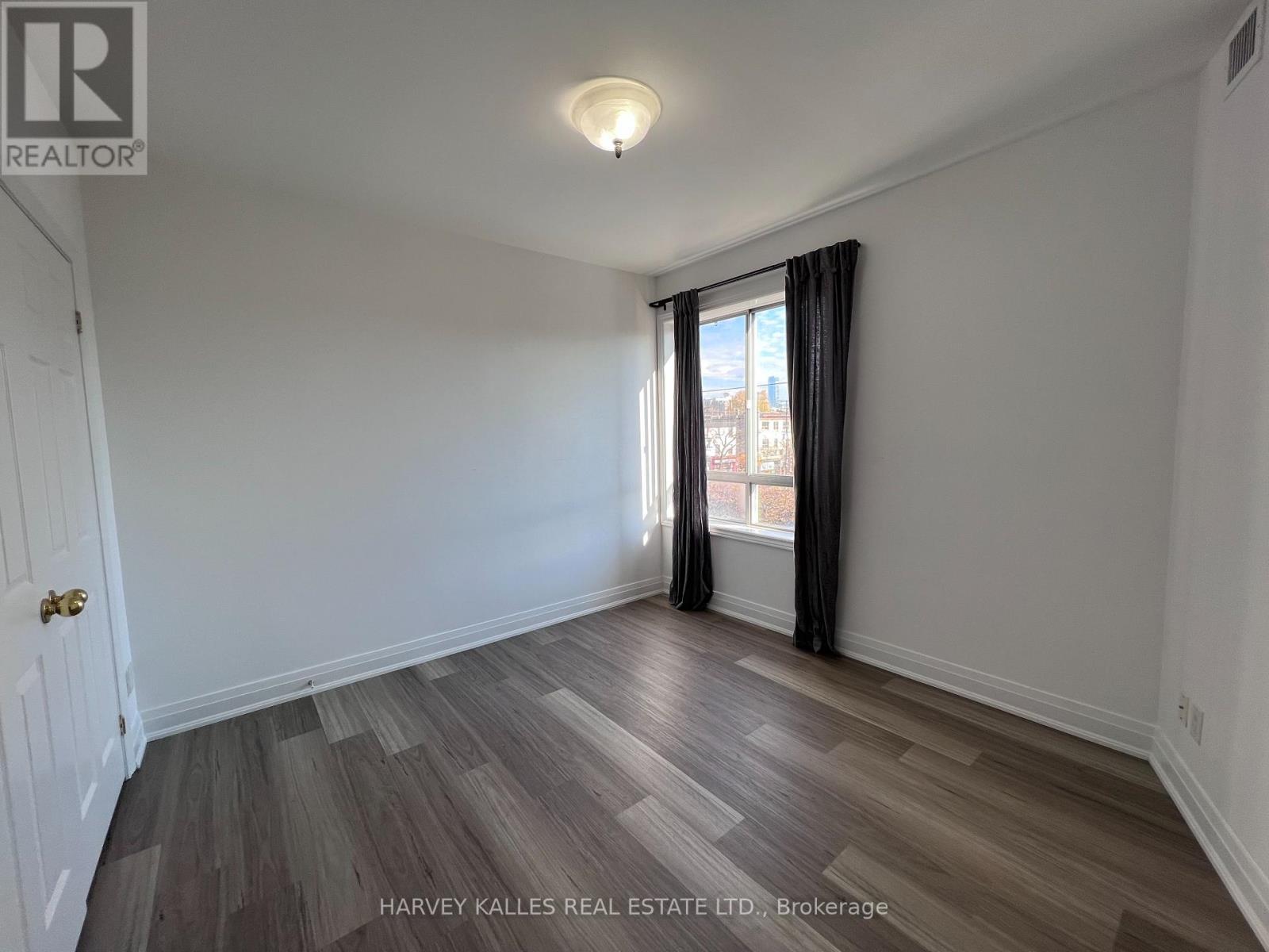 A room with wooden flooring and a window with curtains.