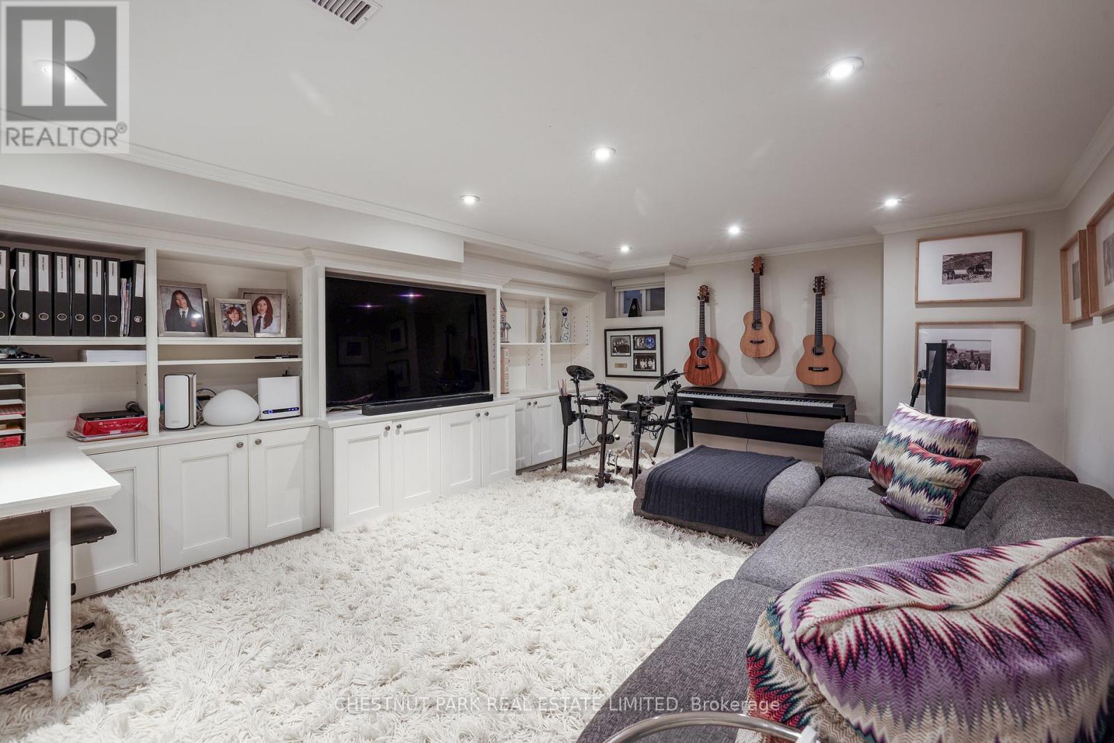 A living room with a grey couch and a guitar hanging on the wall.