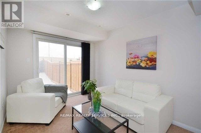 A living room with a white couch, a white chair, and a glass coffee table.