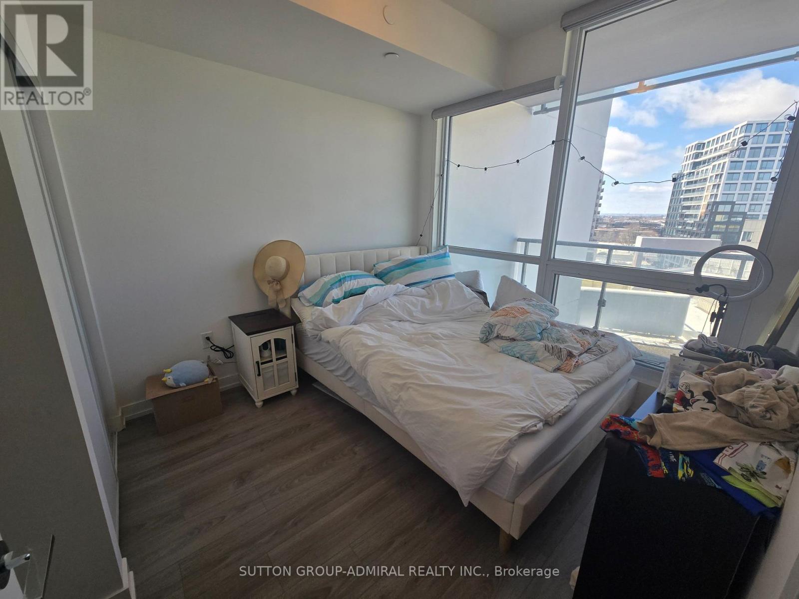 A bedroom with a bed, nightstand, and window overlooking a cityscape.