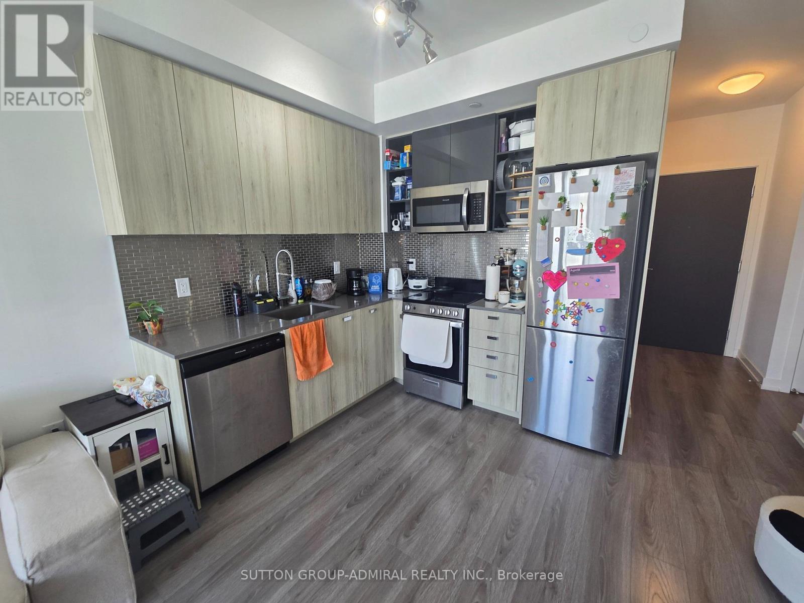 A kitchen with a refrigerator, oven, and sink.