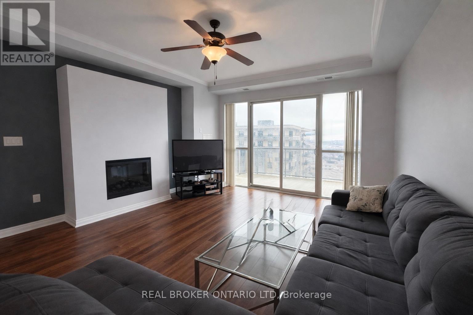 A living room with a grey couch and a fireplace.