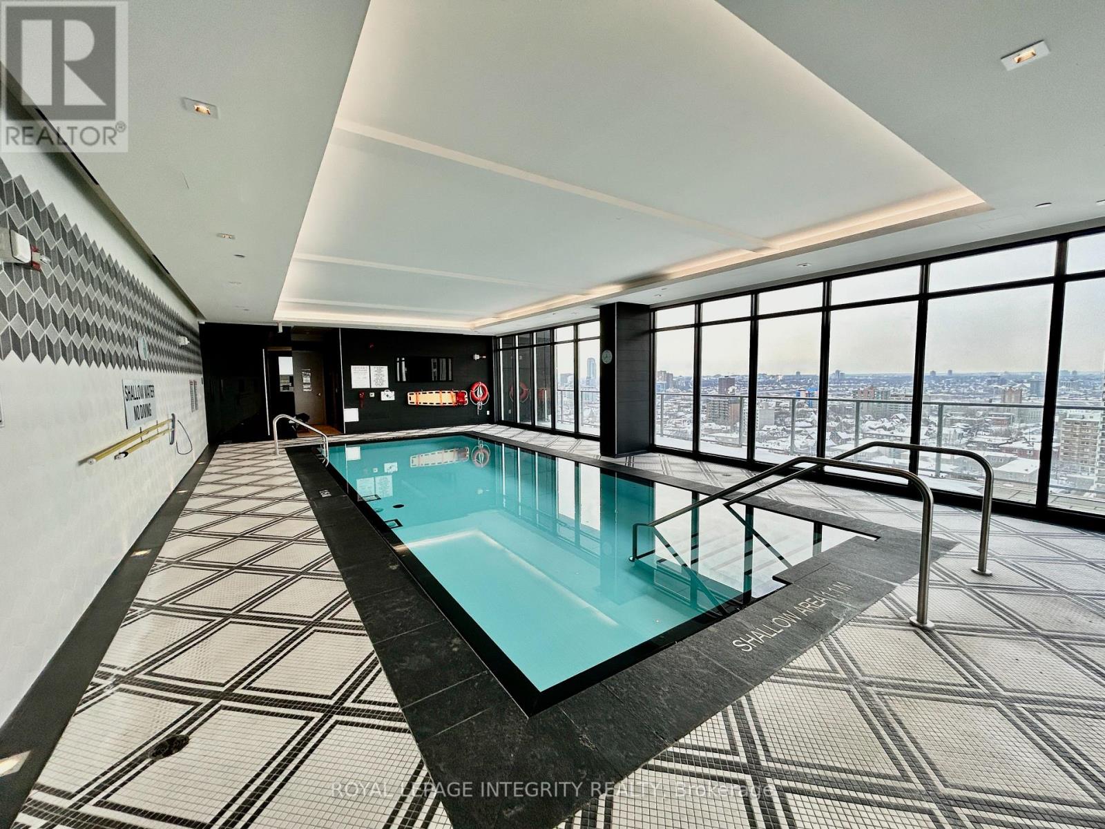 A swimming pool in a room with a view of the city.
