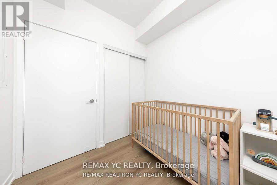 A white bedroom with a crib and a shelf.