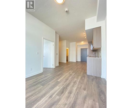 A spacious room with wooden flooring and white walls.