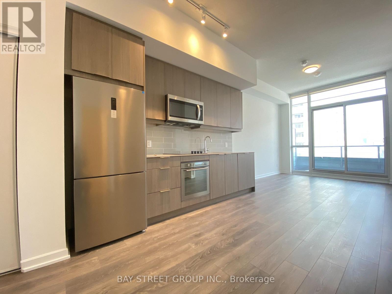 A modern kitchen with a refrigerator, microwave, and oven.