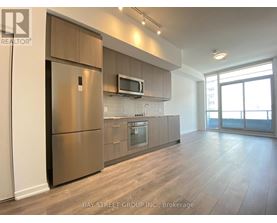 A modern kitchen with a refrigerator, microwave, and oven.