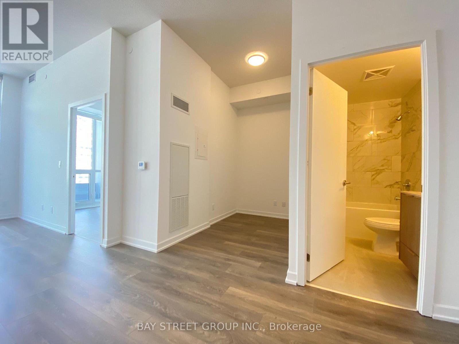 A realtor photo of a white room with a bathroom visible through the door.