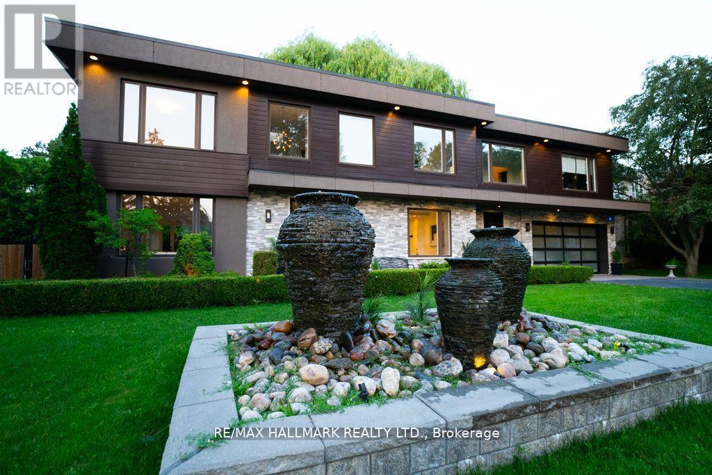 A modern house with a stone fountain in front.